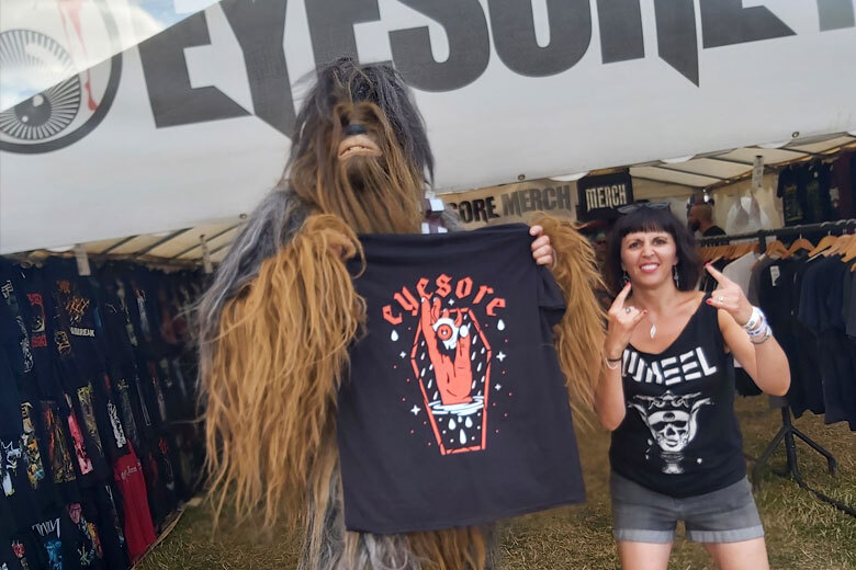 A Wookie and a happy customer pose outside of the Eyesore Merch stall